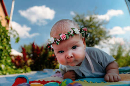 little child lies on a blanket outside, summer, sunny day, visible clouds, clear skyの写真素材