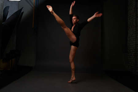 white man in an unbuttoned black shirt and black shorts dancing on a gray background, bare legs and torso, studio shotの写真素材