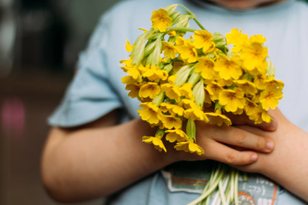 blur. The boy is holding yellow field flowers. gives them - showing in the camera. a gift to mom. to give a bouquet. gift - blurry bouquet of flowers. summerの写真素材