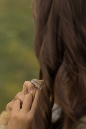 girl with brown hair holds a small, brown with white rabbit in children's hands on a green background, springの写真素材