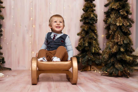 a boy near the Christmas trees on a sled, Christmas lights, rejoices and smiles, plays. holiday and vacationの写真素材