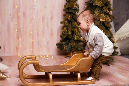 a boy near the Christmas trees on a sled, Christmas lights, rejoices and smiles, plays. holiday and vacationの写真素材