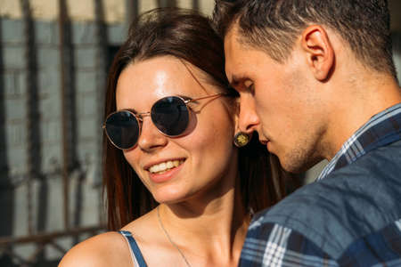 girl in sunglasses smiling. a man is pressed against her cheek, eyes closed.close-upの写真素材