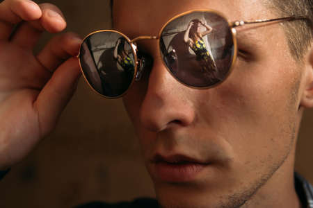 reflection in the glasses of a beautiful girl.portrait of a beautiful young man in sunglasses, which reflects a beautiful girl.guy in sunglasses looks at the girlの写真素材