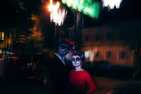 Blur. A man and a woman with a visage, a pattern of skulls, a zombie on the face. Dead at night. A pair of zombies in the dark outside, blurry lights, ghosts. The day of the dead and Halloween.の写真素材