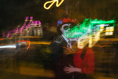 blur of foranium, ghosts of the dead, long exposure. A man and a woman with a visage, a pattern of skulls, a zombie on the face. Dead at night. A pair of zombies in the dark outside, blurry lights, ghosts. The day of the dead and Halloween. long exposure photography, bifurcation.の写真素材