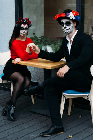A couple, wearing skull make-up for. All souls day. Boy and girl sugar skull makeup.painted for...
