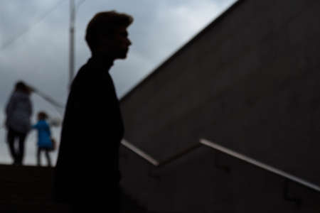 blurred photo, concept on which the male dark is silhouetted against the background of a woman with a child walking away from himの写真素材
