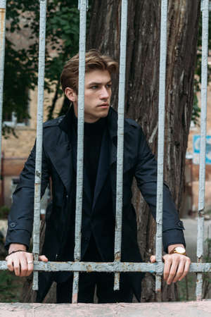 portrait of an attractive young man in a blue suit in the city on gray background.watch on hand, gold wrist watch.pensiveの写真素材