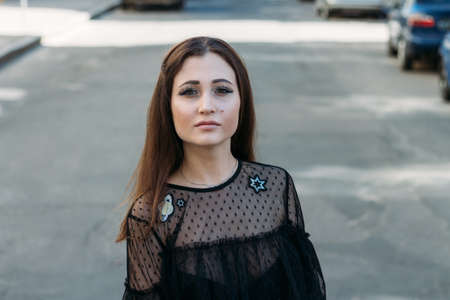 Emotional portrait of Fashion stylish portrait of pretty young woman. city portrait. sad girl. brunette in a black dress with stars and planets on a dress. expectation. dreams. girl - night in the middle of the dayの写真素材
