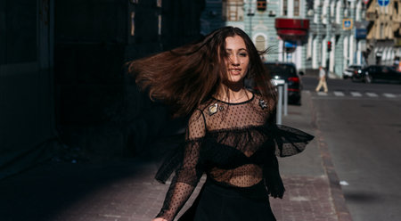 beautiful brunette whirls on a street in the middle of the city, laughs, smiles, happiness, funの写真素材