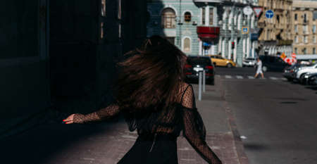 beautiful brunette whirls on a street in the middle of the city, laughs, smiles, happiness, funの写真素材