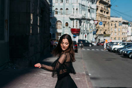 beautiful brunette whirls on a street in the middle of the city, laughs, smiles, happiness, funの写真素材