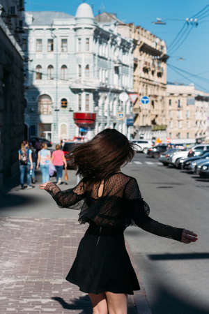 beautiful brunette whirls on a street in the middle of the city, laughs, smiles, happiness, funの写真素材