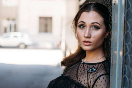 Emotional portrait of Fashion stylish portrait of pretty young woman. city portrait. sad girl. brunette in a black dress with stars and planets on a dress. expectation. dreamsの写真素材