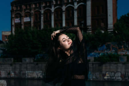portrait of a beautiful girl on the street. brunette in black clothes is sad one in the city on the...