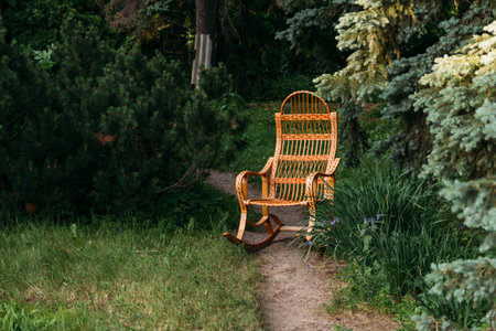 wicker rocking chair made of rattan. old rocking chair made of wood. stands on the road in the woods on the clearing, on the forest path, on the road. privacy and relaxation. handmadeの写真素材