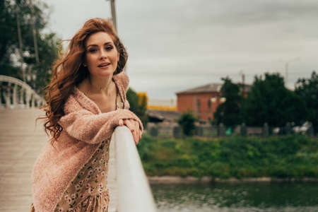 A romantic girl in the city wearing a dress and a sweater of warm colors, her hair develops in the...