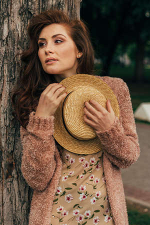 portrait of a brutal, handsome man in a leather jacket on a naked body, with long hair that stands near red flowers, decor. a lonely man is sad and desperate romance and flirtの写真素材