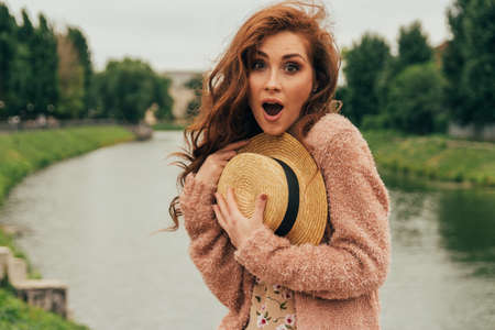 beautiful red-haired girl.picture against the background of the river, water, lake in the park,...