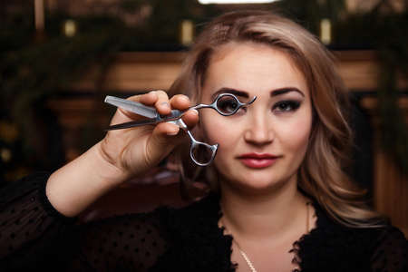scissors in the girl s hand. girl in a black dress with scissors in her hands. preparation for the...