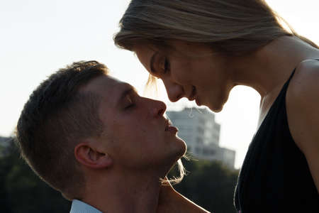 happy loving couple hugging and kissing. dark background, the sun shines on lovers. sun rays in hair, the sun shines on loversの写真素材