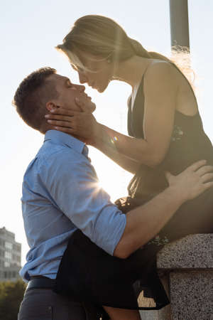 happy loving couple hugging and kissing. dark background, the sun shines on lovers. sun rays in hair, the sun shines on loversの写真素材