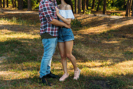 Love and affection between a young couple at the park. a guy in a plaid plane and jeans, a girl in...