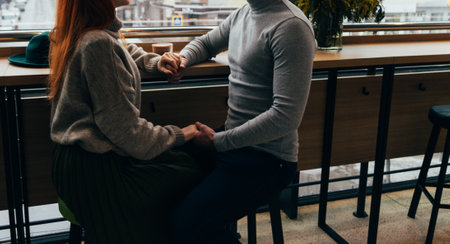The lovely couple in love hold hands in restaurant. couple holding hands sitting on chairsの写真素材