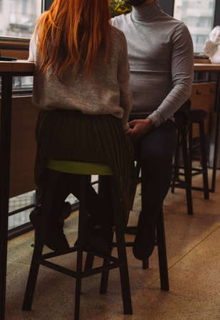 The lovely couple in love hold hands in restaurant. couple holding hands sitting on chairsの写真素材
