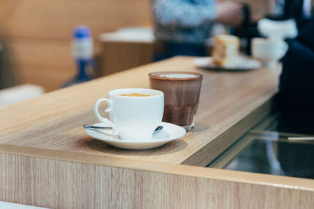 Glass of hot chocolate and cup of cappuccino coffee stand on a table. white cup with a white saucer...