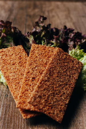 on the wooden table lie salad and dry, bread, crackers, biscuit, crispの写真素材