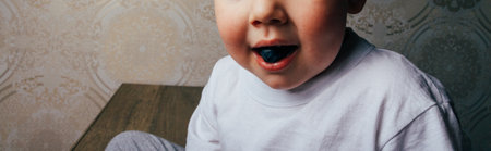 a small boy holds a blueberry berry in his mouth. proper nutrition. fruit. diet. youth. rejuvenation. good mood. healthの写真素材