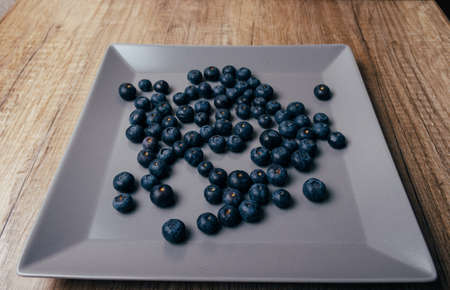 large, fresh blueberries lie on the gray plate, close-up. fruits, nutrition, vitaminsの写真素材