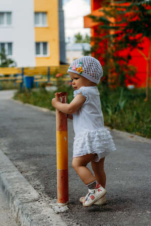 Adorable girl having fun on summer day.a little girl stands on the transition path and clings to the fence, pipeの写真素材