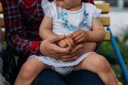 a little girl sits in the arms of a girl, she is hugged behind her back and holding hands.の写真素材