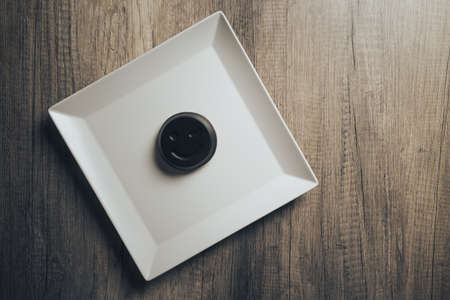Chocolate cookies with a smiling face, winking smile, lie on a white plate standing on a wooden table. place for the inscription. conceptの写真素材