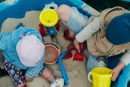 the child is sitting in the sandbox and playing in the sandbox toy balls, sovochkami, rakes and bucketsの写真素材