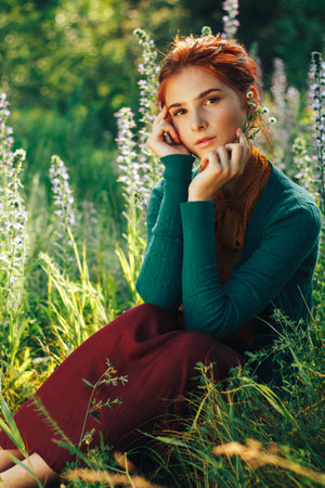 portrait of a beautiful girl with brown hair among the flowers in the field. summer holiday with flowers.の写真素材