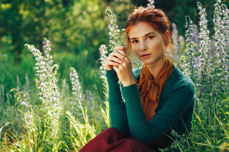 portrait of a beautiful girl with brown hair among the flowers in the field. summer holiday with flowers.の写真素材