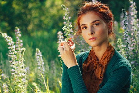 portrait of a beautiful girl with brown hair among the flowers in the field. summer holiday with flowers.の写真素材