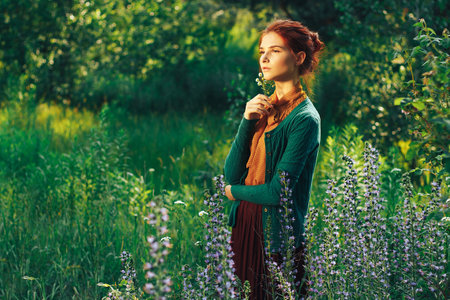 portrait of a beautiful girl with brown hair among the flowers in the field. summer holiday with flowers.の写真素材
