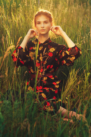 portrait of a beautiful girl with brown hair among the flowers in the field. summer holiday with flowers.の写真素材