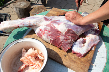 male hands cut, cut meat Butcher preparing meat outdoors during a traditional festival raw meat legの写真素材