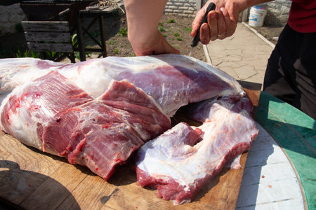 male hands cut, cut meat Butcher preparing meat outdoors during a traditional festival raw meatの写真素材