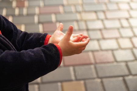 a small child catches raindrops, splashes fly into his face, closes his eyes. rainy weather. wet...