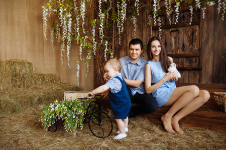 family in the village, with rabbits in their arms. little boy with mom and dad. white rabbitsの写真素材