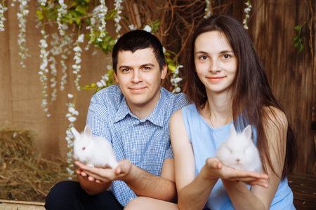 family in the village, with rabbits in their arms. little boy with mom and dad. white rabbitsの写真素材