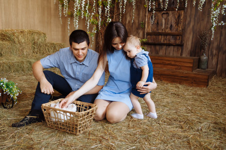 family in the village, with rabbits in their arms. little boy with mom and dad. white rabbitsの写真素材