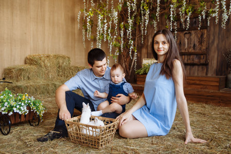 family in the village, with rabbits in their arms. little boy with mom and dad. white rabbitsの写真素材